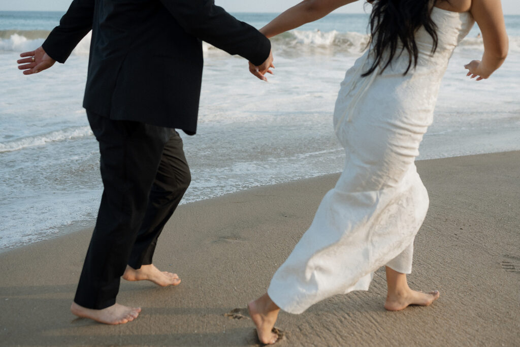 newly married couple running around laguna beach 