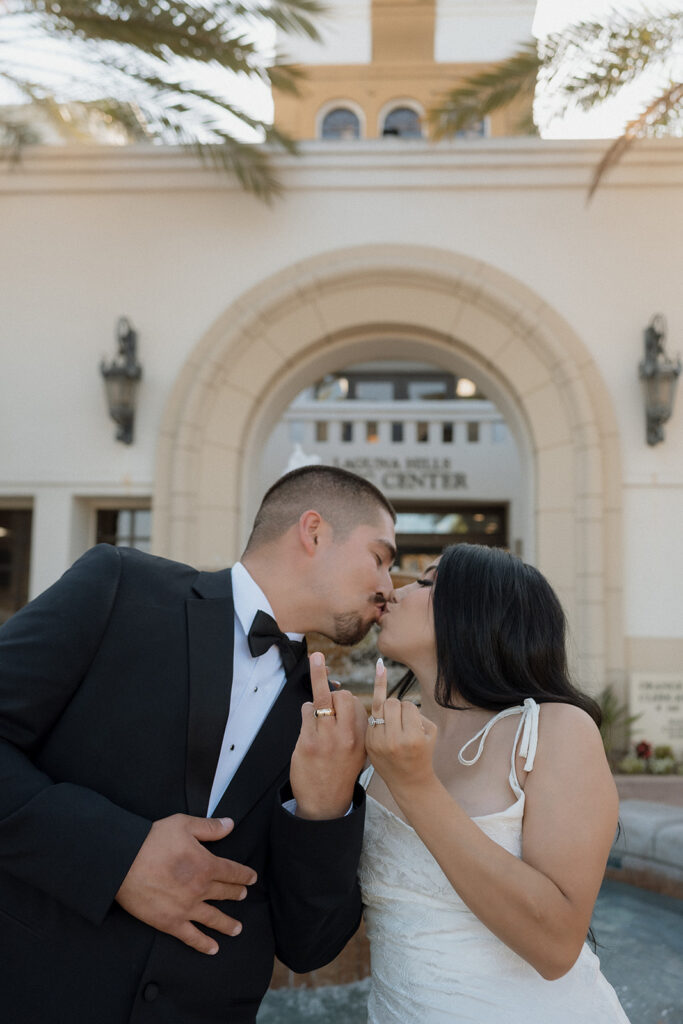 newly married couple kissing and showing their wedding rings 