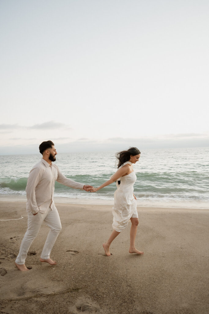 couple holding hands walking around the beach 