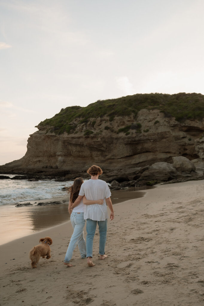 cute couple hugging walking around the beach 