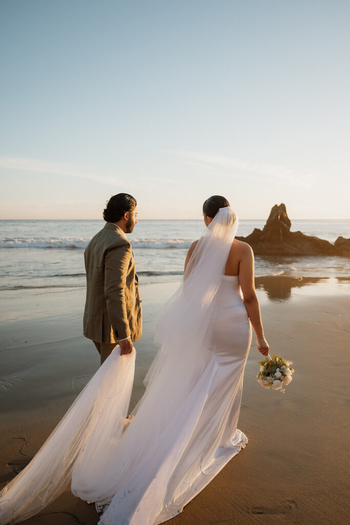 couple holding hands walking around the beach 