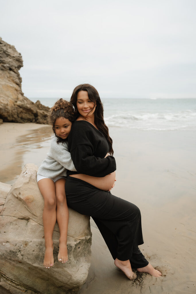 cute picture of the soon to be mom and her daughter at their beach photoshoot